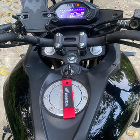 AUSZUOI keychain clipped to motorcycle ignition for reliable on-bike use