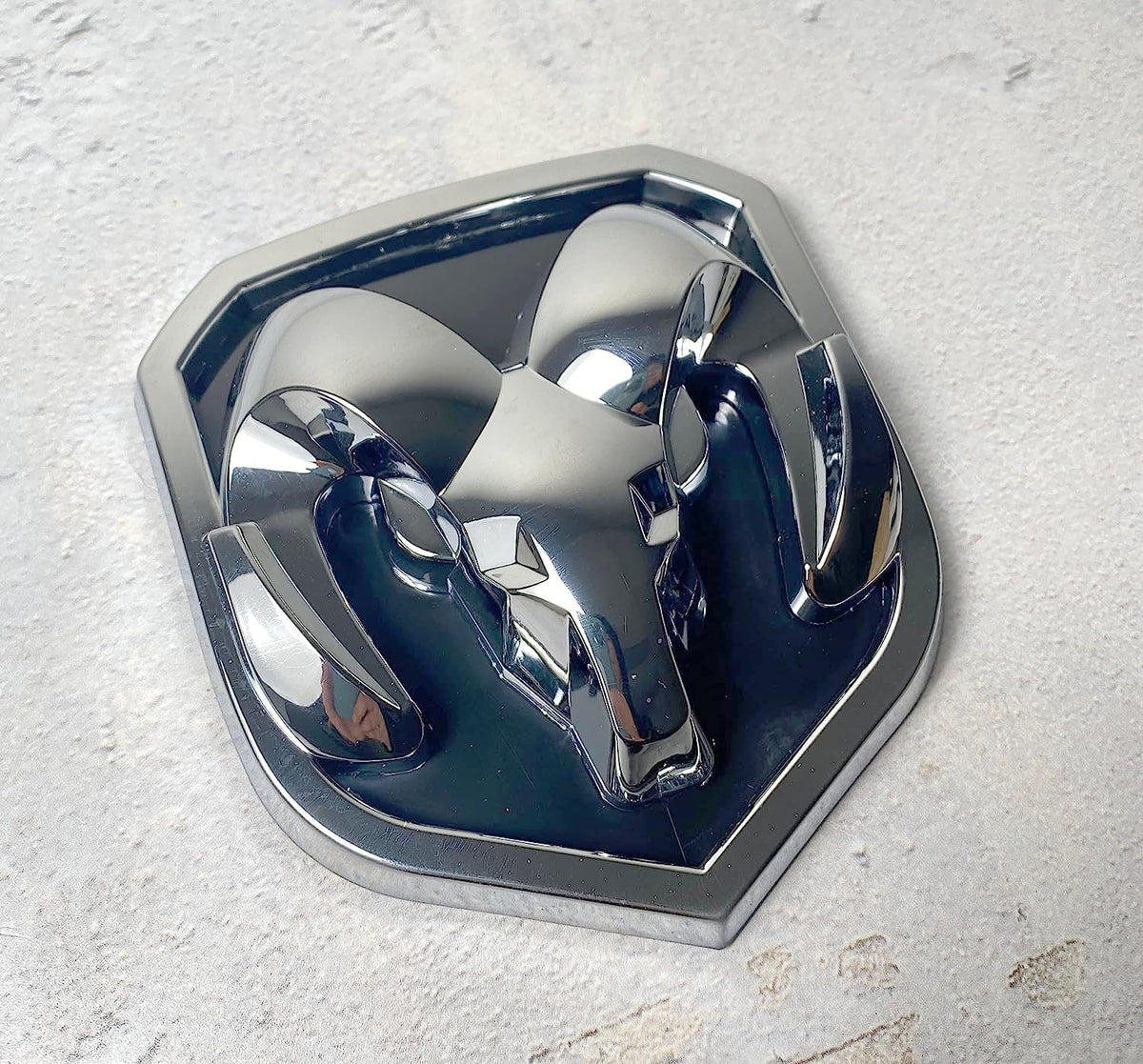 Autogem chrome RAM emblem held in hand to show scale and precise fitment