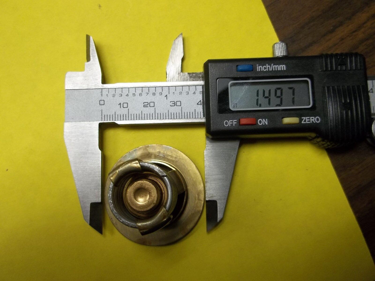 B. toys thermostat beside ruler for size comparison to confirm proper fitment