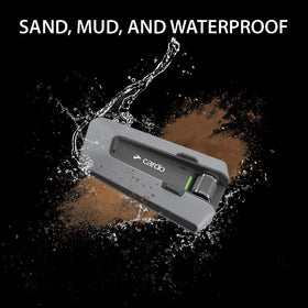 Cardo PACKTALK Edge ORV mounted on helmet with mud splash proving waterproof durability