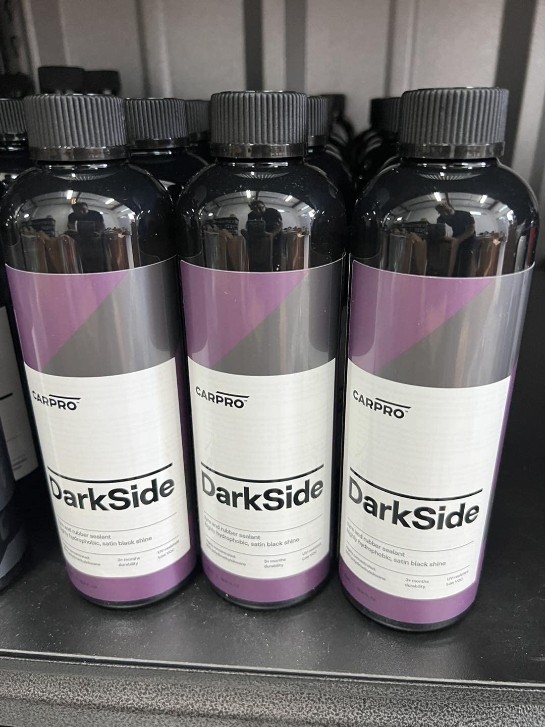 CARPRO DarkSide on vehicle tire in driveway lifestyle shot showing showroom-ready look