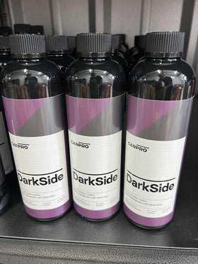 CARPRO DarkSide on vehicle tire in driveway lifestyle shot showing showroom-ready look
