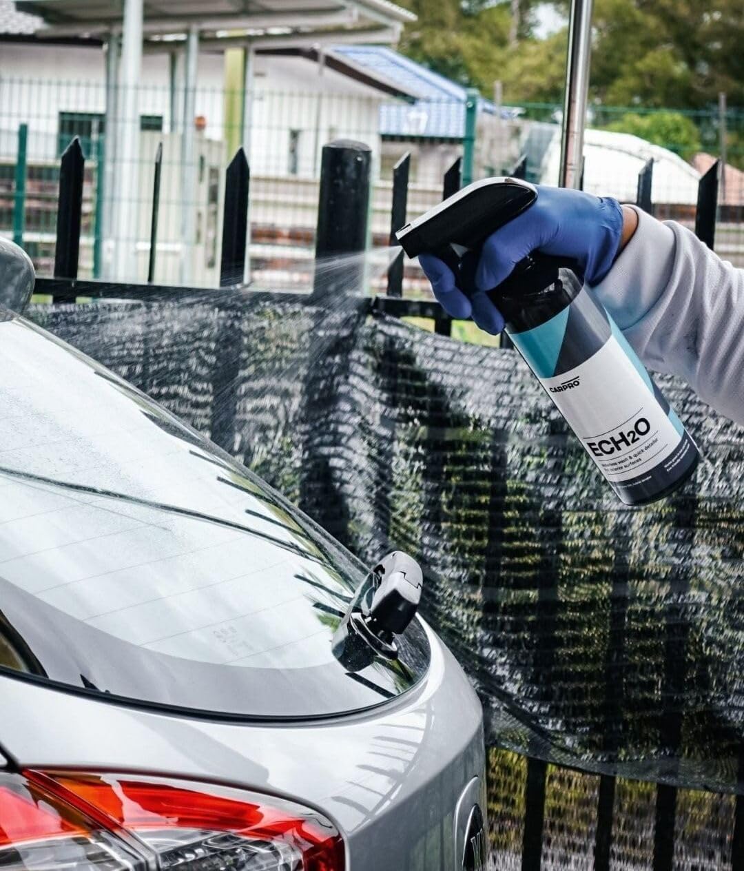 Spraying CARPRO ECH2O on a car panel illustrating safe waterless application