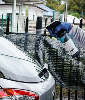 Spraying CARPRO ECH2O on a car panel illustrating safe waterless application