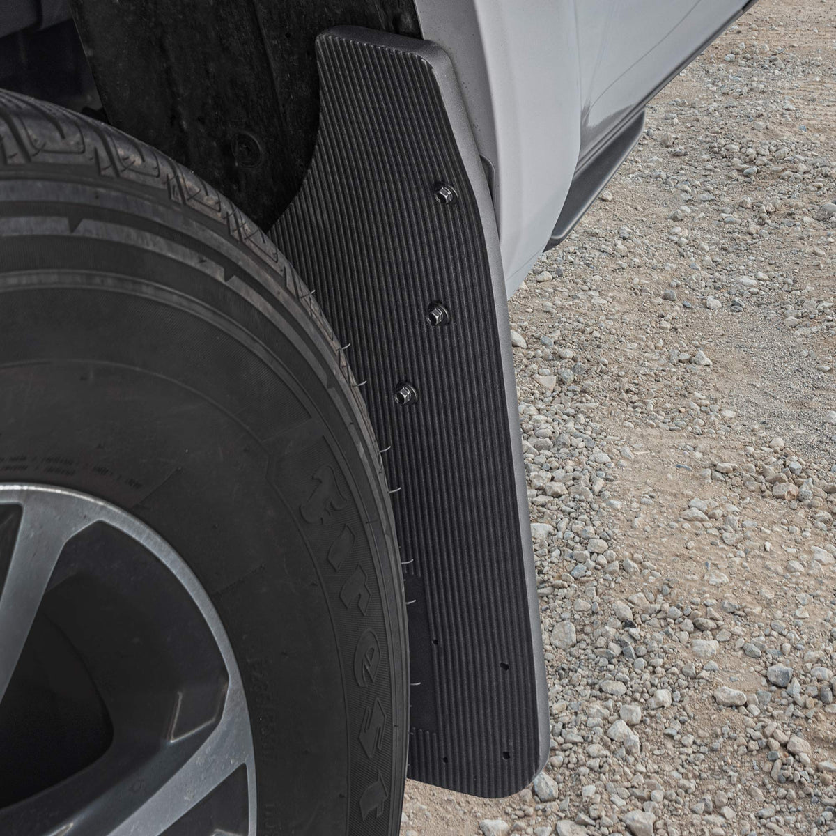 CAT mud flap on truck driving dirt road protecting undercarriage