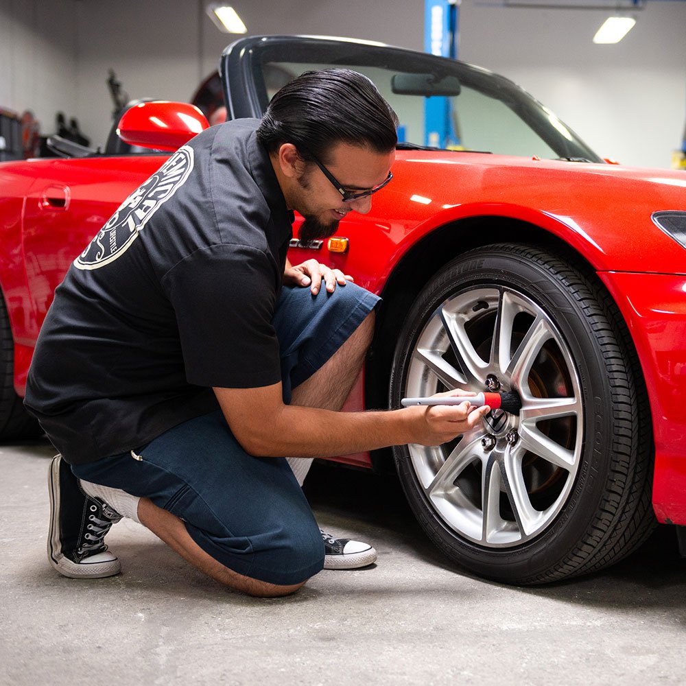 Chemical Guys brush used on a textured grille for precise dirt removal and finish care