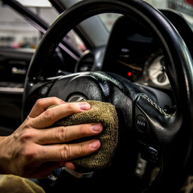 Chemical Guys applying serum to car seat demonstrating protection and conditioning benefit