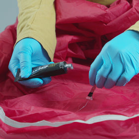 GEAR AID tube beside camping gear illustrating compact size and portability