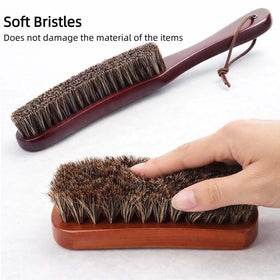 Generic curved long-handle horsehair brush close-up cleaning a hat brim for precise dust removal