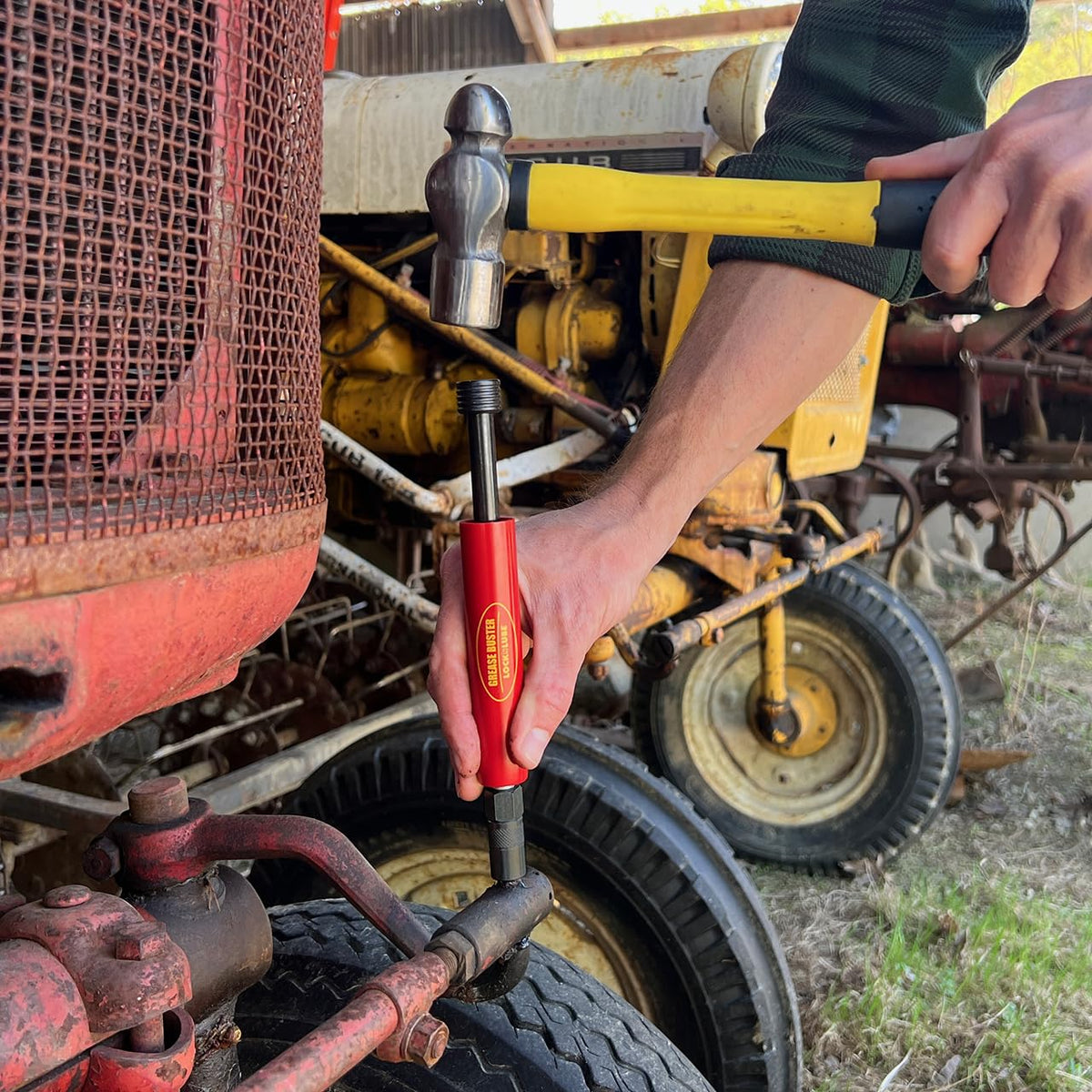 Grease Buster in use by Grease Buster flushing a tractor pivot pin to restore lubricant flow