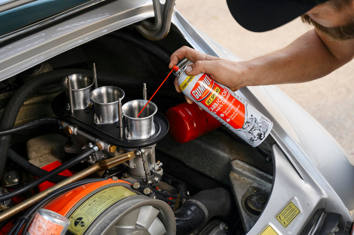 Gumout spraying into carburetor throat to remove varnish and gum
