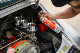 Gumout spraying into carburetor throat to remove varnish and gum