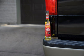 Gumout bottle in a garage setting showing practical maintenance for high-mileage vehicles