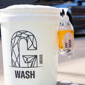 Gyeon 500ml bottle beside measuring cup showing dilute-to-use convenience