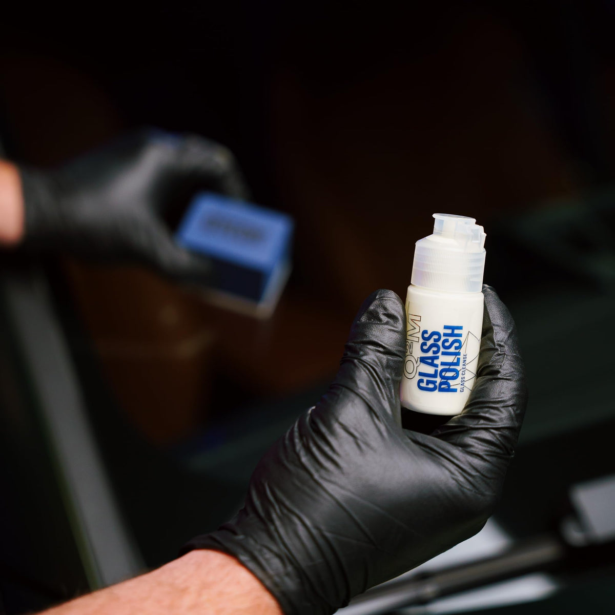 Gyeon bottle next to a hand to show compact travel-friendly size