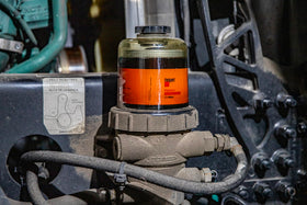 Hot Shot's Secret one-gallon bottle next to a hand for scale to show workshop volume