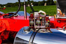 One-gallon Hot Shot's Secret beside a fuel nozzle to show size and value