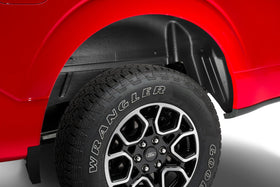 Husky Liners guard next to tire for scale showing coverage area and fit on wheel well
