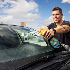 Invisible Glass being sprayed on car windshield demonstrating quick cleaning