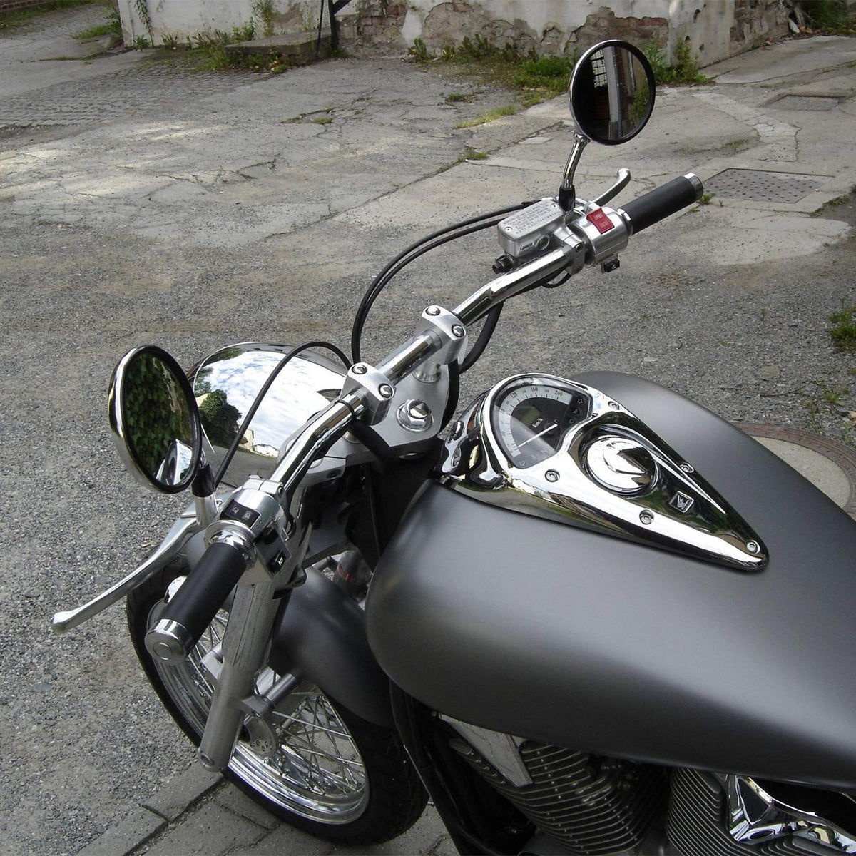 KEMIMOTO riser on a parked motorcycle in street setting showing comfort benefit
