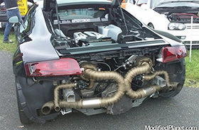 Mechanic fitting LEDAUT titanium header wrap in garage to lower under-hood heat