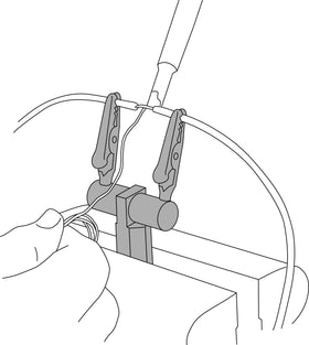 Lisle clamp in use on workbench holding wire for safer, hands-free soldering