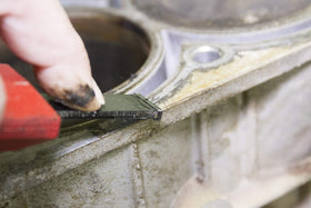 Lisle scraper in use removing gasket residue from an aluminum cylinder head for clean sealing