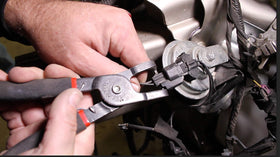 Lisle pliers in use on a fuel line demonstrating reach and hands-free control