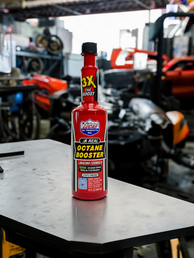 Lucas Oil octane booster on a garage workbench with tools showing ready-to-use convenience for mechanics