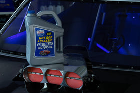 Lucas Oil five-quart next to spark plug showing size and application