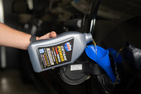 Lucas Oil cetane power booster next to a diesel engine illustrating system protection