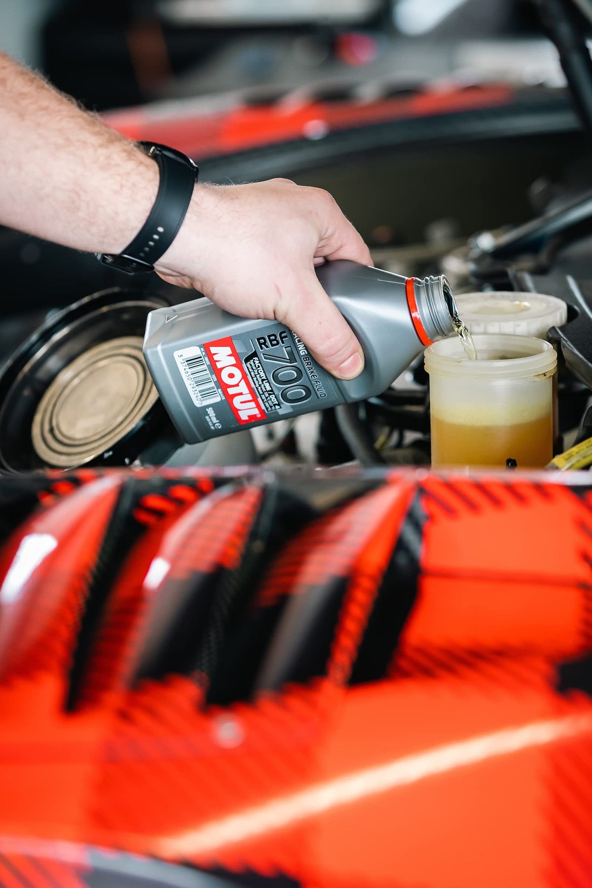 Motul RBF 700 bottle beside brake disc for scale, showing suitability for performance brakes
