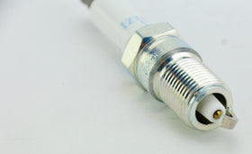 NGK next to a coin for scale communicating plug size and easy identification