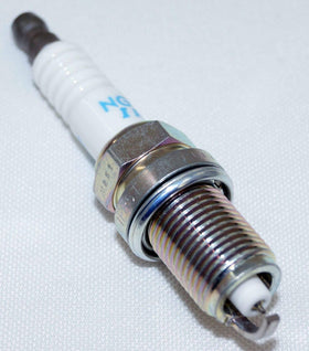 Four NGK IFR5T11 plugs arranged on white surface showing new condition
