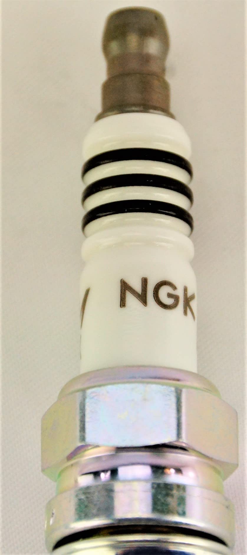 NGK plug next to coin for scale showing compact design and correct reach