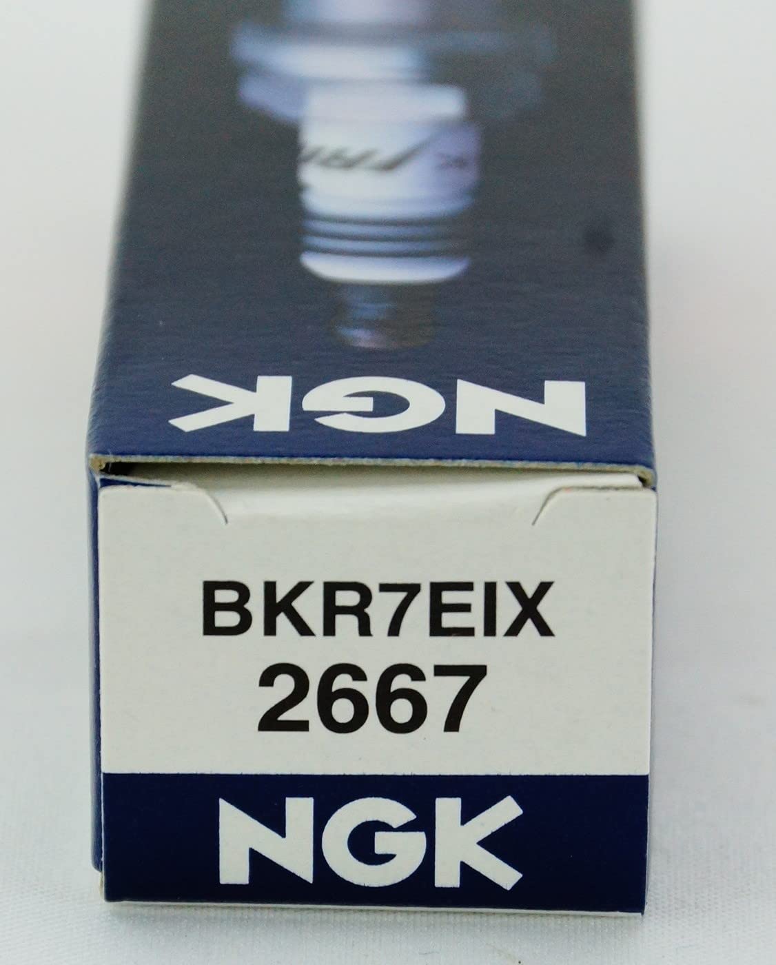 NGK spark plugs on workbench lifestyle scene conveying trusted durability
