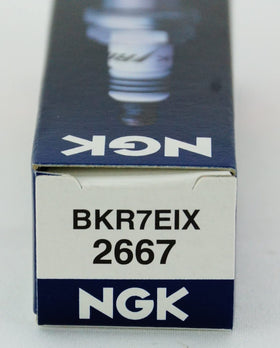 NGK spark plugs on workbench lifestyle scene conveying trusted durability