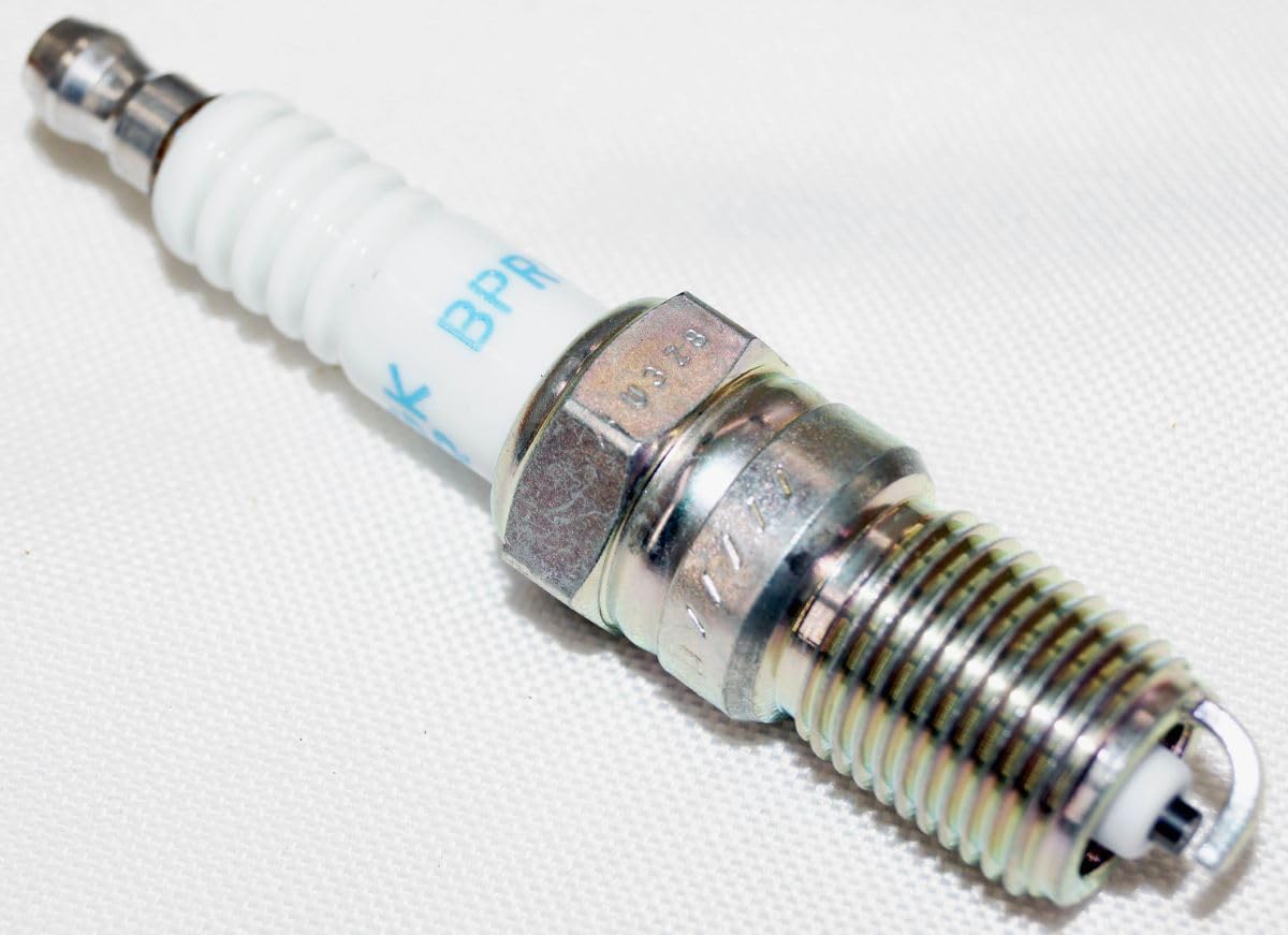 Technician using torque wrench on NGK plug showing correct tightening to recommended range