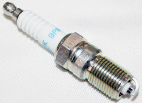 Technician using torque wrench on NGK plug showing correct tightening to recommended range