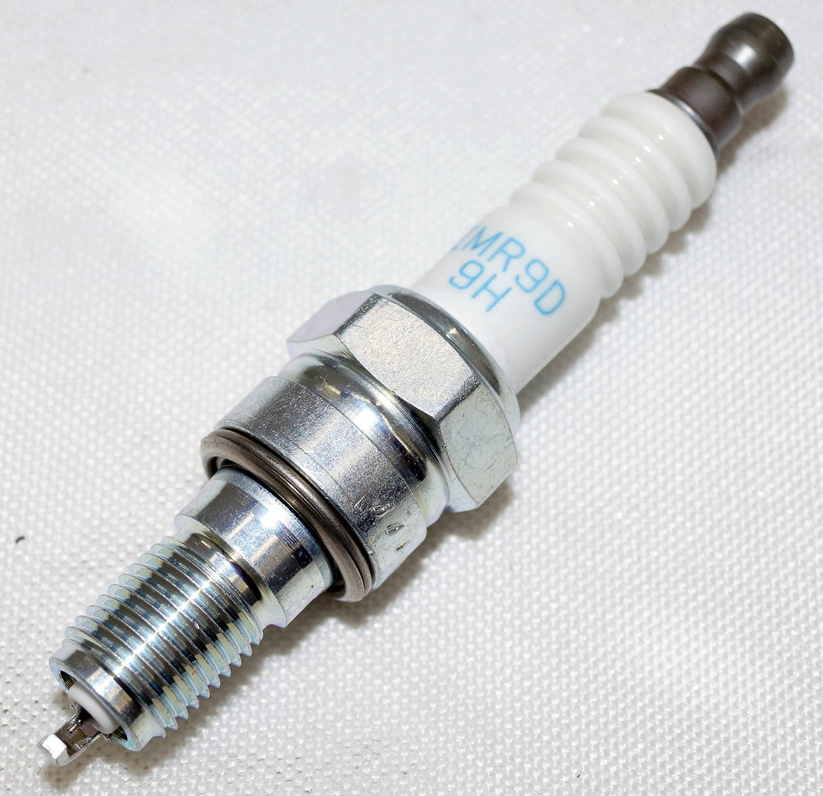 NGK spark plug beside ruler showing size and correct fitment benefit