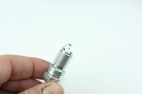 NGK spark plugs on workshop bench in garage scene implying professional-grade replacement