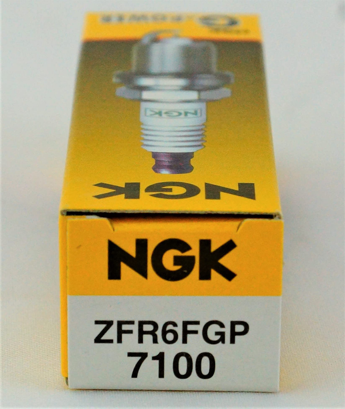 NGK spark plug beside ruler showing scale for accurate sizing and fit confirmation