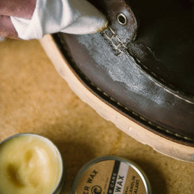 Applying Otter Wax to a leather boot to create a water-resistant protective layer