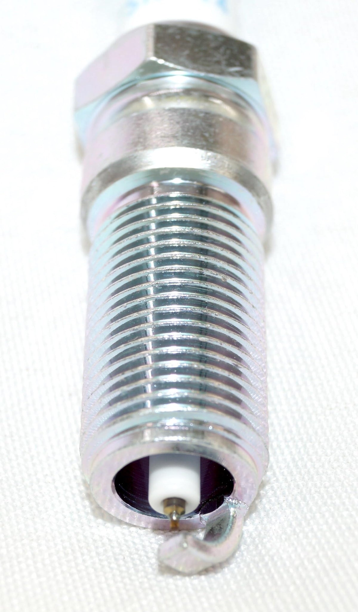 OVERSTOCKDIRECT spark plug held in hand to show scale and thread length for straightforward comparison