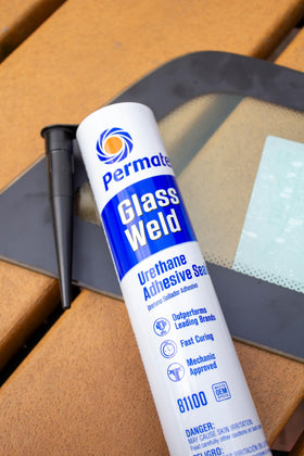 Permatex Glass Weld cartridge next to caulking gun illustrating size and ease of use
