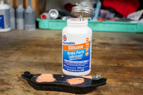 Permatex on pad backing plate preventing metal‑to‑metal noise and wear