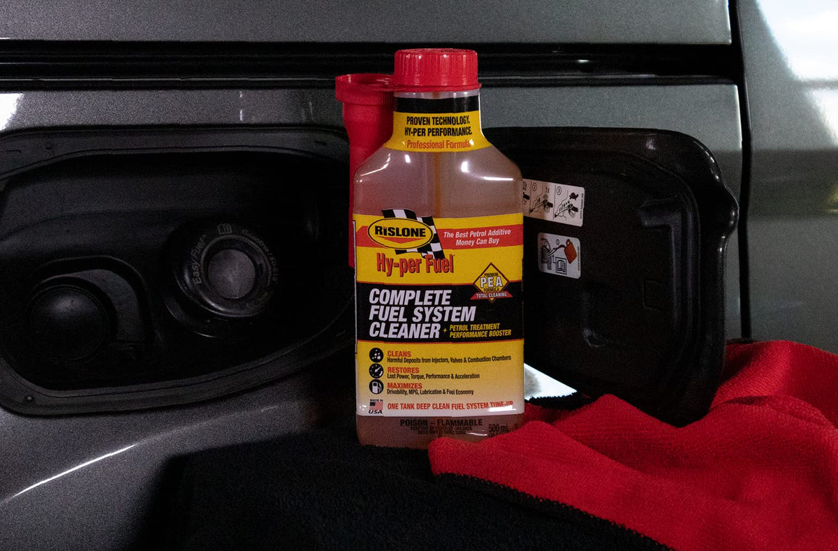 Rislone in a garage beside a car demonstrating regular maintenance benefits