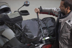 ROK Straps securing luggage on a motorcycle rack, reflective thread visible, safer transport
