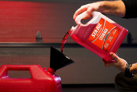 STA-BIL storage being added to a lawn mower fuel tank to ensure easy seasonal starts