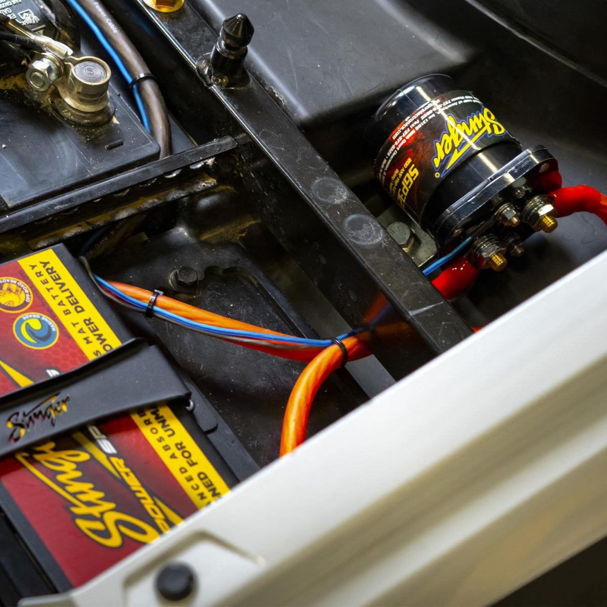 STINGER SGP32 next to a car battery showing compact size and installation scale
